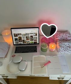 an open laptop computer sitting on top of a desk next to a heart shaped light