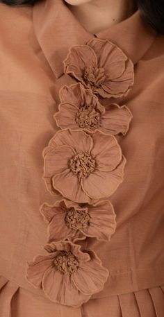 a woman wearing a brown dress with flowers on the front and back of her neck