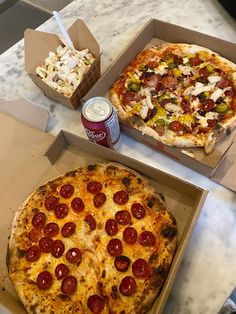 two pizzas in boxes on a table