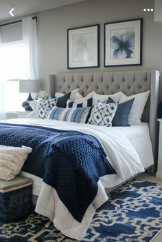 a bed with blue and white pillows in a bedroom next to two pictures on the wall