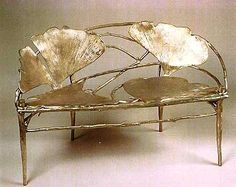 a metal bench with two chairs sitting on it's back legs and one seat is shaped like leaves