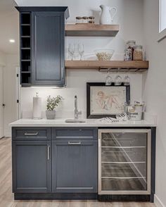 a kitchen with gray cabinets and white counter tops, wooden flooring and open shelving above the sink