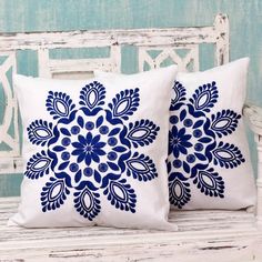 two blue and white pillows sitting on top of a wooden bench