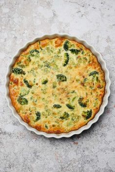 broccoli and cheese quiche in a pie pan on a gray table top