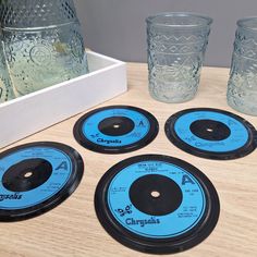 four blue and black records sitting on top of a wooden table next to two glasses