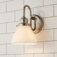 a bathroom light with a white glass shade on the wall next to a brick wall