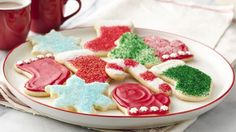 decorated christmas cookies on a plate next to a cup of coffee