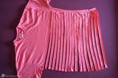 a pink top with pleating on the front and bottom, sitting on a purple surface