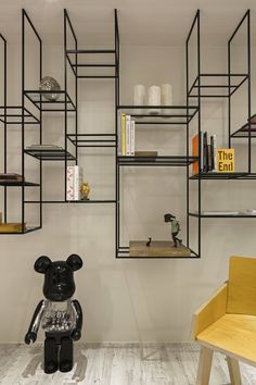 a teddy bear sitting in the middle of a room with bookshelves and shelves