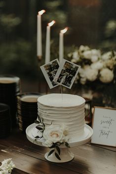 a wedding cake with two photos on top and flowers in the middle, sitting on a table