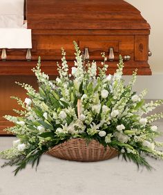 a basket filled with white flowers sitting on top of a floor next to a piano