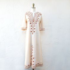 70's Ivory cotton kaftan embroidered in white and tan. This pretty boho maxi dress has elbow length bell sleeves. There are no darts. It is fitted at the waist and zips up the back. Size small fits like a current size 4 Measurements with room for comfort: Bust up to: 33 inches Waist up to: 30 inches Hips up to: 36 inches Exact measurements taken flat to compare to a garment which fits well: Length: 52 inches. Sleeve length:14 inches. Shoulders across the back: 16 inches. Bust: 17 inches. Waist: Embroidered Cream Kaftan For Summer, Cream Embroidered Kaftan For Summer, Cream Bohemian Maxi Dress With Floral Embroidery, Bohemian Cream Maxi Dress With Floral Embroidery, Beige Embroidered Bohemian Maxi Dress, Beige Maxi Length Kaftan For Spring, Cream Embroidered Kaftan For Spring, Cream Embroidered Maxi Dress, Blush Lace Dress