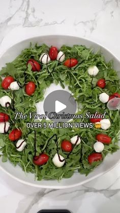 a salad with tomatoes and mozzarella on it in a white bowl sitting on top of a marble counter