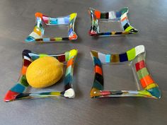 four pieces of art glass sitting on top of a wooden table next to a lemon