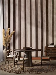 a table and chairs in front of a wall with vertical striped panels on the walls