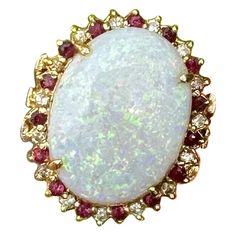 This is a stunning Retro - Hollywood Regency Ring with a gorgeous central 9.57 Carat Opal surrounded by a halo of 30 absolutely radiant Rubies and Diamonds in 14 Karat Gold. The magnificent monumental oval opal cabochon gem is 21 mm by 16 mm by 5mm deep. The opal radiates vivid blue, green, yellow, orange and red and and is absolutely wonderful! The 15 sparkling white round diamonds alternate with 15 round faceted rubies of a gorgeous vivid red. The jewels are set in a lovely gallery in 14 Karat Yellow Gold. The combination of the stunning 10 Carat oval Opal of impressive size surrounded by the halo of sparkling red and white rubies and diamonds is absolutely wonderful! The ring will make every occasion it appears at the most glamorous affair. It is just fabulous. Opal The oval opal caboch Regency Ring, Luxury Ruby And Diamond Oval Cabochon Ring, Luxury Victorian Style Cabochon Ruby Ring, Antique Ruby Cabochon Ring, Victorian 14k Gold Cabochon Opal Ring, Luxury Victorian Ruby Cabochon Ring, Retro Hollywood, Auto Correct, Rubies And Diamonds