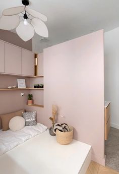 a bed room with a neatly made bed next to a wall mounted shelf and a ceiling fan