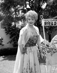 an old photo of a woman standing next to a planter with flowers in it