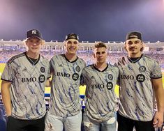 three men standing next to each other in front of a stadium