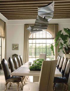 the dining room table is surrounded by black leather chairs and an array of greenery