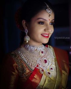 a woman in a red and gold sari with pearls on her head, smiling at the camera