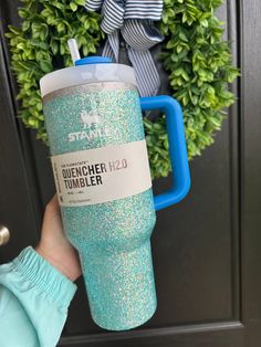 a person holding up a starbucks cup in front of a door with a wreath on it