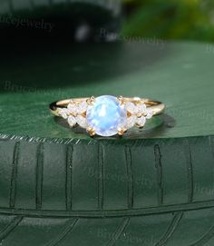 a ring with a blue stone surrounded by white diamonds on top of a green surface