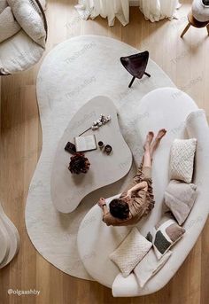 a woman laying on top of a white couch in a living room