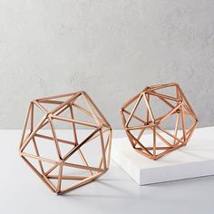 two geometrically shaped objects sitting on top of a white table next to each other