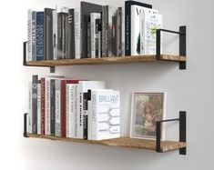 two wooden shelves with books on them against a white wall, one has a black metal shelf and the other holds several books