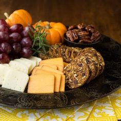 a platter filled with cheese, crackers and grapes