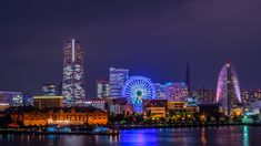 the city skyline is lit up at night, with ferris wheel visible in the foreground