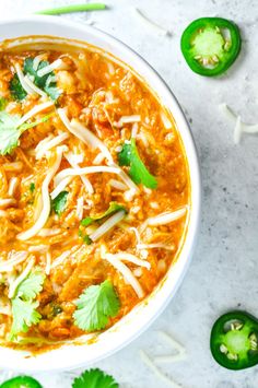 a white bowl filled with soup and garnished with cilantro, parsley and green peppers