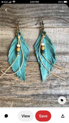 the turquoise feather earrings with beads are hanging from hooks on a wooden surface and wood planks