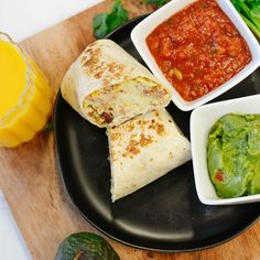 a black plate topped with burritos and salsa