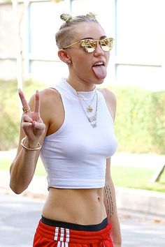 a woman making the peace sign with her hand while wearing red shorts and white top