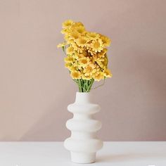 a white vase with yellow flowers in it