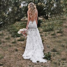 a woman in a wedding dress is walking through the desert with her bouquet on her shoulder