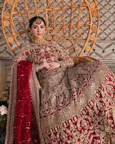 a woman in a red and gold bridal gown sitting on a chair