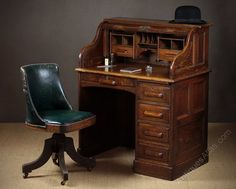 an old wooden desk with a green chair next to it and a black hat on top