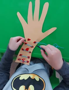 a child is making a handprint out of paper with the batman symbol on it