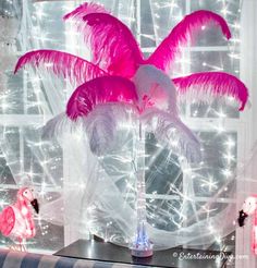 pink and white decorations in front of a window with lights on the windowsills