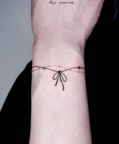 a woman's wrist with a small tattoo on the left side of her arm