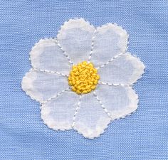 a white flower with yellow center sitting on top of a blue fabric covered table cloth