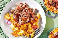 a white plate topped with meat and vegetables next to two bowls of macaroni and cheese