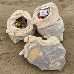 two mesh bags filled with items sitting in the sand