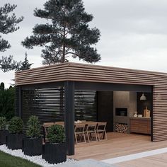 an outdoor dining area with wooden decking and black planters on the side of it