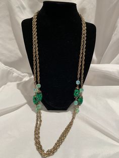 This stunning statement piece is a vintage signed Coro opera length necklace.  The glimmering green oval beads are flanked by cut iridescent beads, which adorn a 60-inch gold tone chain.   Whether worn long or doubled, it's a show-stopper. Elegant Green Oval Bead Necklaces, Elegant Green Oval Beaded Necklaces, Elegant Green Necklaces With Oval Beads, Green Beaded Evening Jewelry, Green Oval Jewelry For Evening, Party Jewelry With Oval Beaded Chain, Elegant Green Beaded Chain Necklace, Vintage Double Strand Chain Jewelry, Vintage Metal Jewelry With Faceted Beads