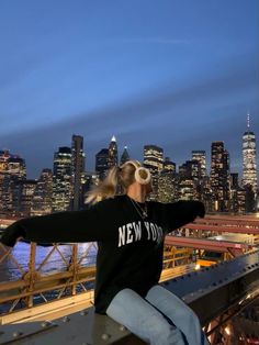 a woman standing on top of a bridge next to a city