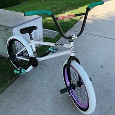 a white and purple bike parked on the side of a road next to a box